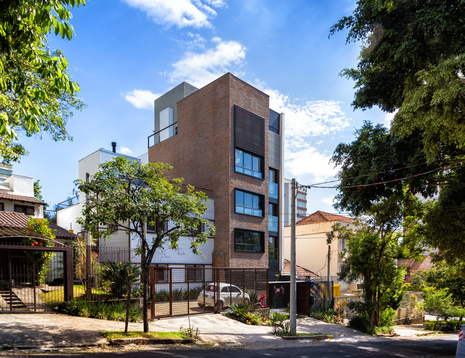 A fachada de tijolos do Edifício Casa América vista da rua, entre árvores.